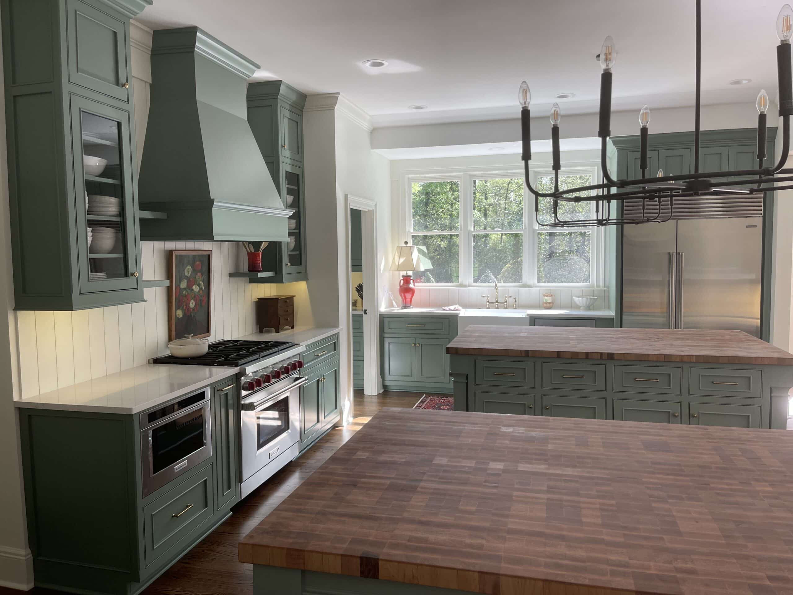 Custom kitchen with green cabinetry, a large island, and hardwood floors